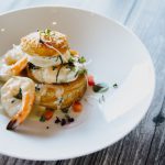 French Cuisine - a white plate topped with food on top of a wooden table