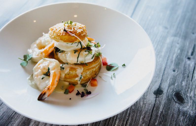 French Cuisine - a white plate topped with food on top of a wooden table