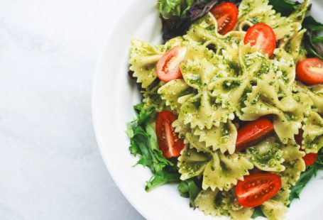 Italian Cuisine - Pesto pasta with sliced tomatoes served on white ceramic plate