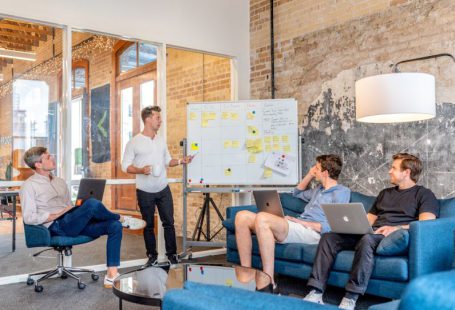 AgriTech Startup - three men sitting while using laptops and watching man beside whiteboard