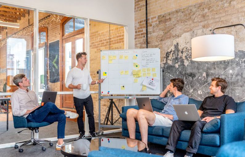 AgriTech Startup - three men sitting while using laptops and watching man beside whiteboard
