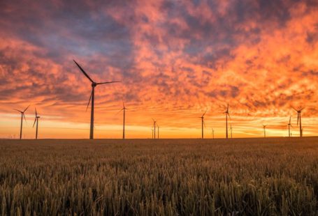 Climate Change Agriculture - landscape photography of grass field with windmills under orange sunset