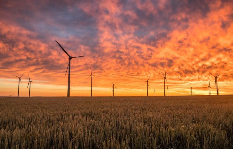 Climate Change Agriculture - landscape photography of grass field with windmills under orange sunset