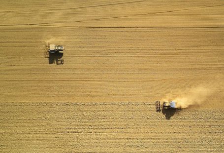 Biotech Farming - aerial view of two harvesters on brown field
